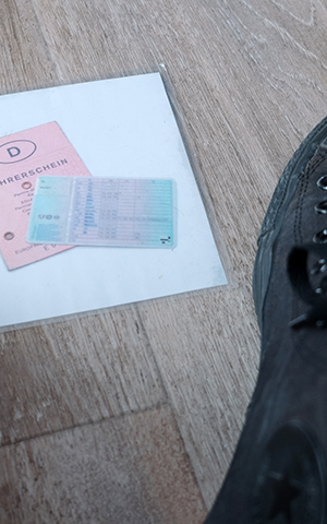 Führerschein und Fahrzeugpapiere liegen auf dem Boden neben einem Stiefel